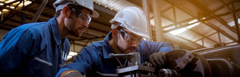 Picture of 2 men in a factory working on a machine