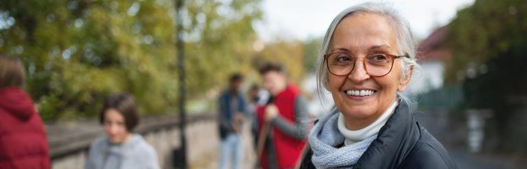 Picture with a woman at the forefront, and people behind tidying up a path